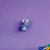 Blue cartoon character on a purple wall with toys on a green surface below.